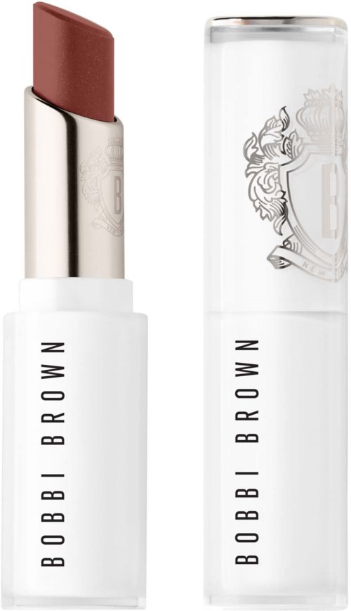 A lipstick with a white case and black lettering, next to a clear cap with logo. The lipstick is a nude shade.