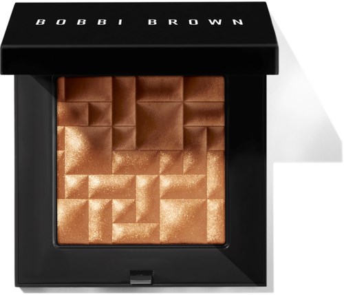 A black compact with a shimmering bronze highlighter. The top lid has 'BOBBI BROWN' written on it.