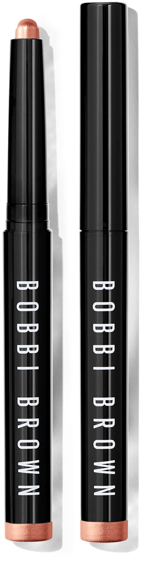 Two black makeup sticks with white text saying "BOBBI BROWN," one open showing a light blush color and the other closed.