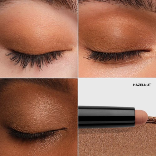Close-up of eyelids with makeup and a beige lipstick tube labeled 'Hazelnut' nearby.