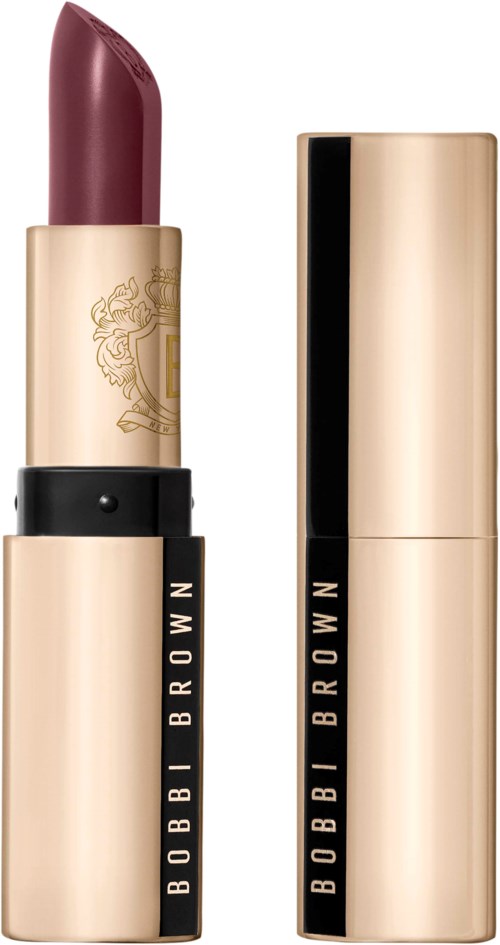 A Bobbi Brown lipstick in a gold and black tube, shadowed, with the cap removed showing the lipstick.
