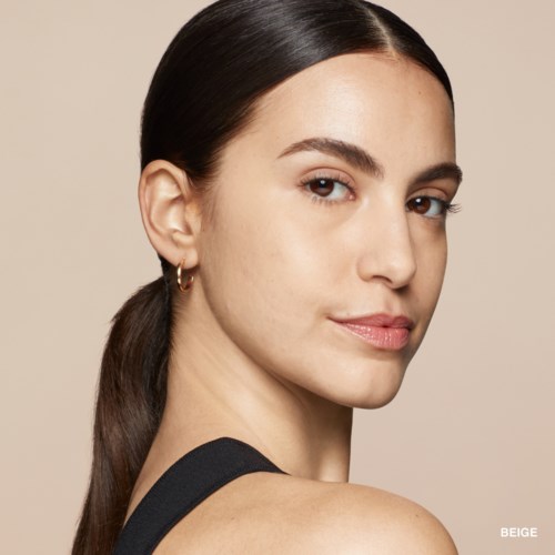 A young woman with fair skin and dark brown hair tied back, wearing a black sleeveless top and small gold hoop earrings.