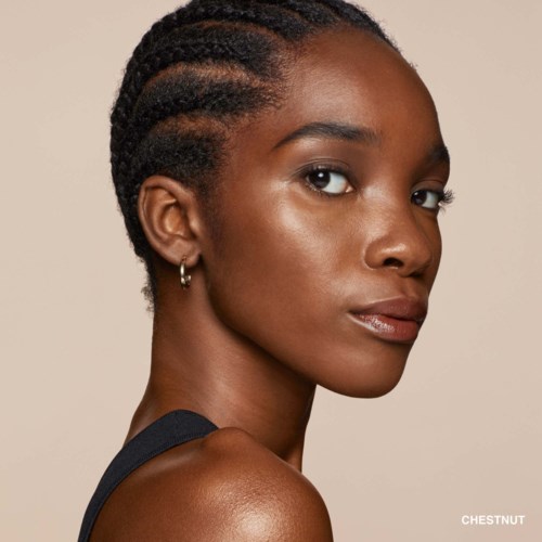 Young woman with braided hair, wearing a dark top, looking over shoulder with neutral expression.