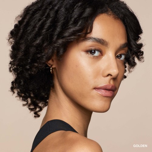 A woman with curly black hair and earrings looks confidently at the camera, wearing a black top.