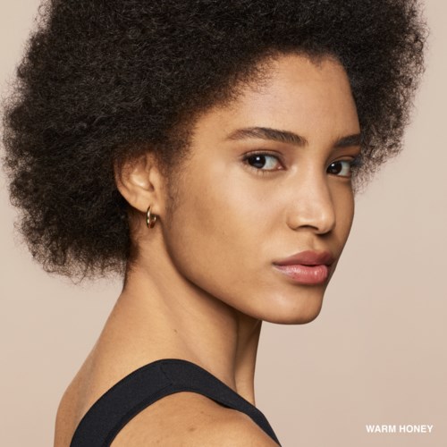 A woman with natural curly hair, golden skin, and wearing a black top, looking confidently at the camera.