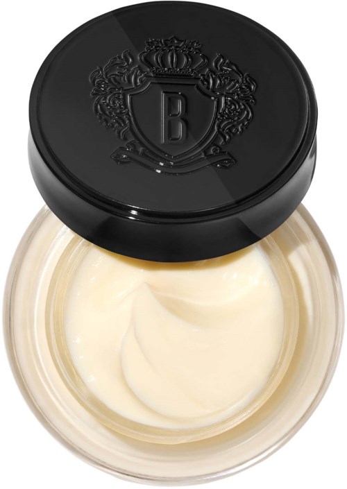 A small jar of cream with a black lid featuring an ornate shield and crown design.