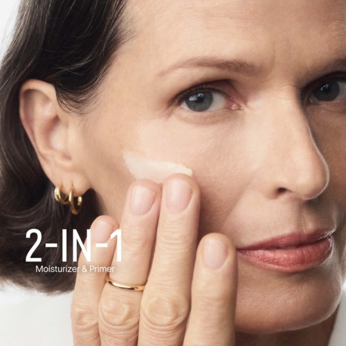 A woman with fair skin applies moisturizer to her face, promoting a 2-in-1 skincare product. She has short dark hair.