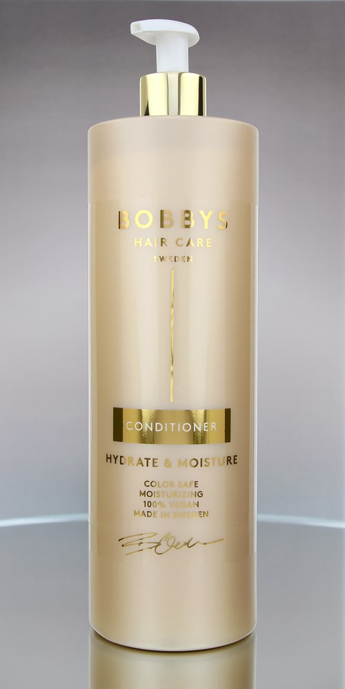 En høy, beige flaske med pumpe. Gulldetaljer og teksten 'BEBYS Hair Care' og 'CONDITIONER' på den.