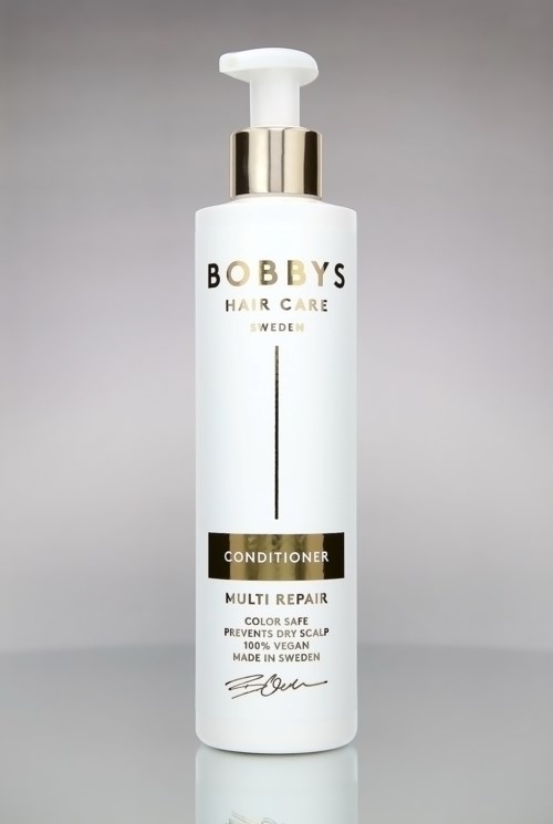Eine weiße Flasche mit goldenen und schwarzen Akzenten, als Bobbys Haarpflege Conditioner bezeichnet, für Mehrfachreparatur und Kopfhautgesundheit.