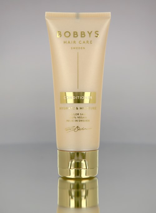 Eine beige und goldene Tube von Bobby's Hair Care Spülung, für Feuchtigkeit und Farbpflege, mit einfachem Design.