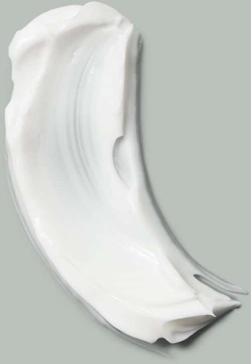 Ein gebogener Streifen aus weißer Creme oder Lotion auf grauem Hintergrund.