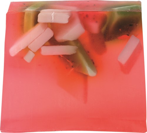 Een roze zeep met kleine stukjes fruit en kruiden erin. Het ziet kleurrijk en verfrissend uit.