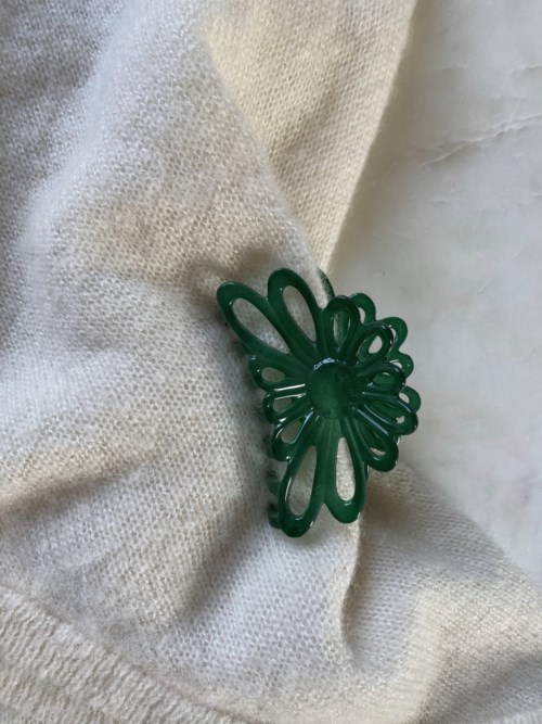 Green plastic butterfly-shaped brooch pinned on fabric.