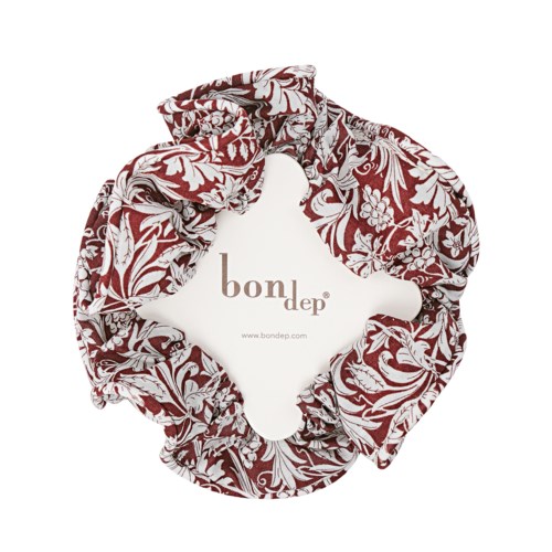 Hårstrikk med rødt og hvitt blomsterdesign og Bondep-logo inni.