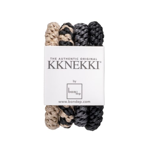 Tre nystan av tjock, crankig garn i beige, svart och mörkgrå färger i en vit låda.