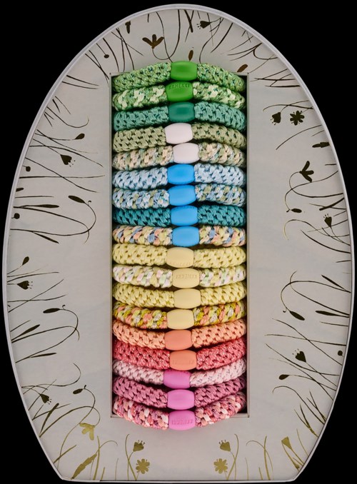Colorful hair ties arranged vertically on a decorative oval mirror background.