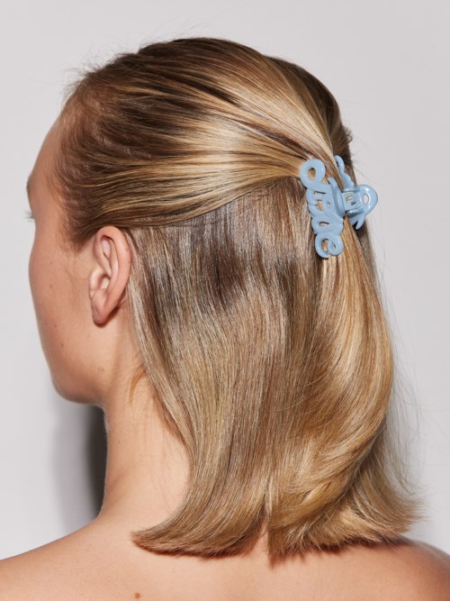 A woman with blonde hair has a blue hair clip saying "Hello".