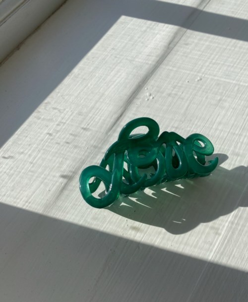 A green decorative word 'love' placed on a light-colored surface with sunlight and shadows.