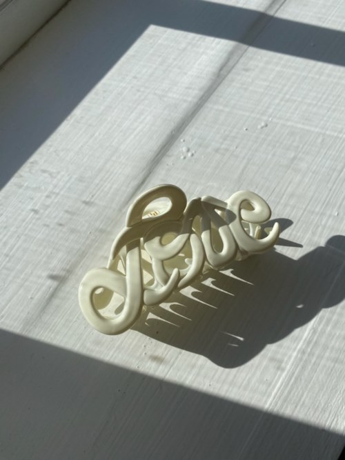Cream-colored decorative word 'love' on a white surface with shadows.