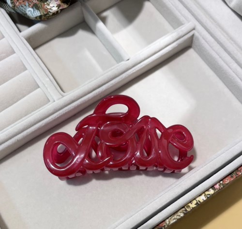 A red, shiny, decorative word 'love' in cursive, placed in a white jewelry box.