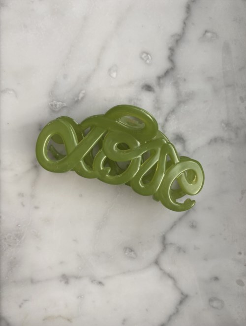 Ett grönt ord 'love' gjort av plast, ligger på en vit marmoryta.