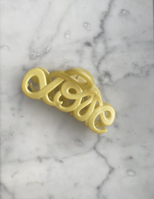 Ett gult plastföremål formad som ordet "love" på en marmor yta.