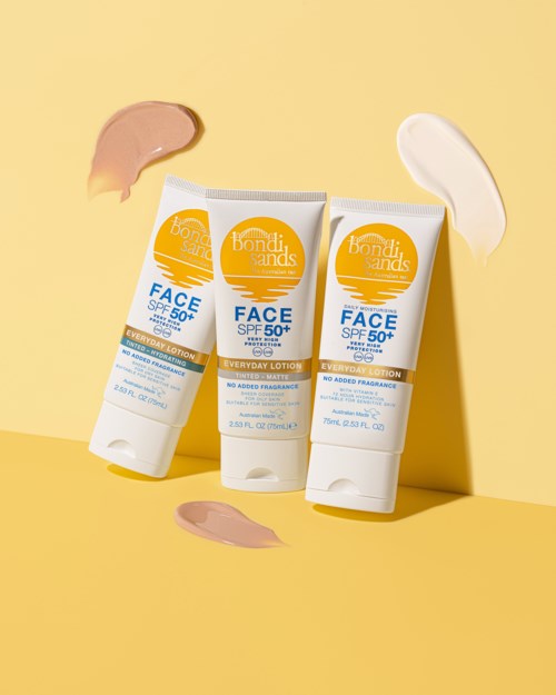 Three tubes of sunscreen with SPF 50+ on a yellow background, with cream smears around them.