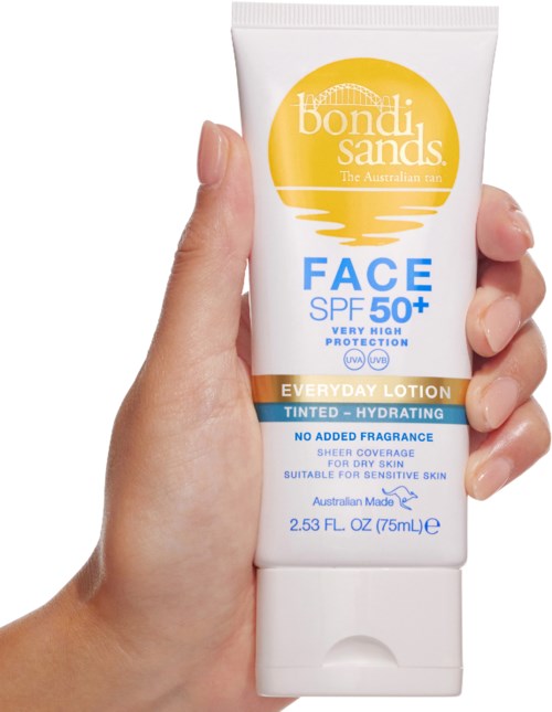 Eine Hand hält eine weiße Tube von Bondi Sands getönter, feuchtigkeitsspendender Gesichtscreme mit SPF 50+ für empfindliche Haut.