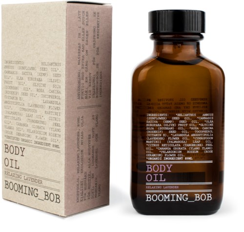 Eine braune Glasflasche mit der Aufschrift 'Body Oil' und 'Relaxing Lavender' neben einer Pappschachtel mit Produktinformationen.
