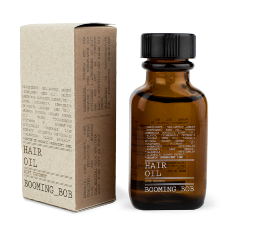 Eine braune Glasflasche mit der Aufschrift 'Hair Oil' und eine beige Verpackung, beide für das Produkt Booming Bob Haaröl.