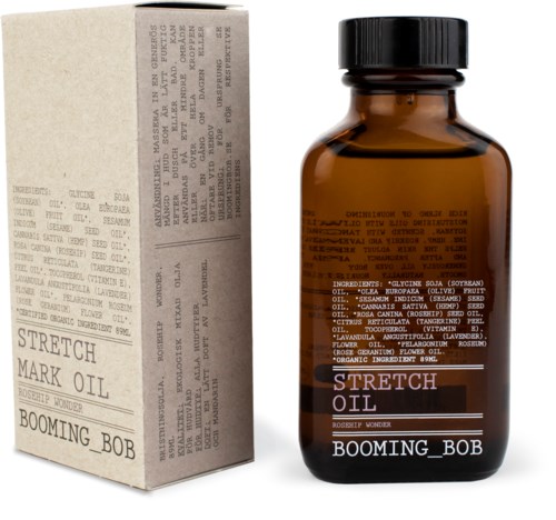 Kleine bernsteinfarbene Flasche mit Label 'Stretch Oil' und 'Booming Bob' neben einem weißen Karton mit Text.
