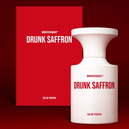 Een parfumfles met 'DRUNK SAFFRON' daarop staat naast een rood doosje, beiden met eenvoudige witte en rode ontwerpen.