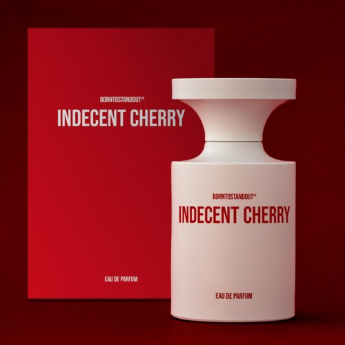 Een witte parfumfles met de tekst "Indecent Cherry" naast een rood doosje met dezelfde tekst, op een donkerrode achtergrond.