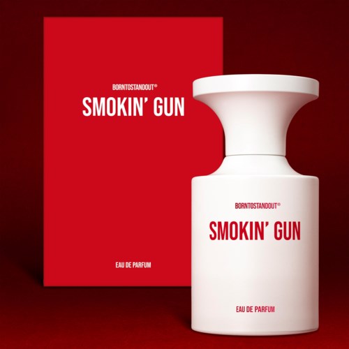 Een witte parfumfles met brede top en een rood doosje erachter, allebei gelabeld "SMOKIN' GUN."