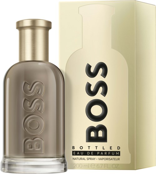 Ein Parfümflasche und eine Verpackung. Die Flasche ist rund mit goldener Kappe und 'BOSS' geprägt. Die Verpackung ist cremefarben mit 'BOSS' geschrieben.