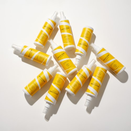 Kleine gele flessen met witte doppen, verspreid op een witte achtergrond.