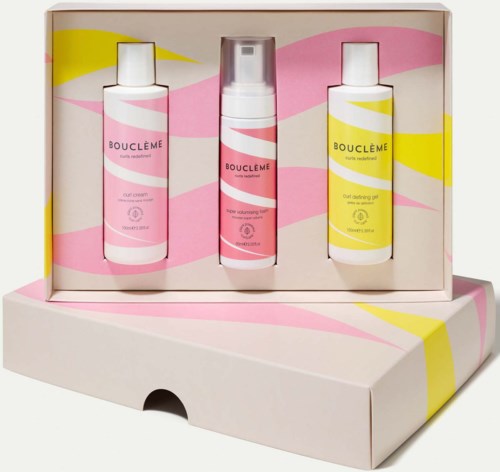 Drie flessen Bouclème-haarproducten in een roze, gele en witte doos.