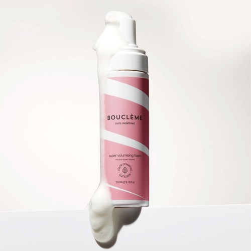 Een roze en witte fles Bouclème super volumising foam met een gebogen ontwerp en witte dop.