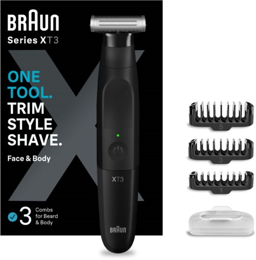 A black electric shaver with three attachments, a power button, and a green indicator light, lying in front of its box.