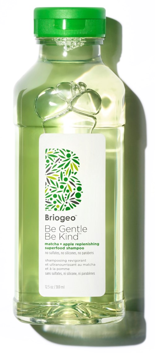 Een doorzichtige fles met groene dop bevat appelgekleurder water, label 'Briogeo Be Gentle Be Kind'.