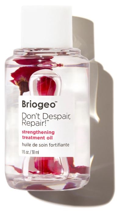 De afbeelding toont een doorzichtige fles met versterkende treatment olie, met een witte dop en een roze bloem binnen.