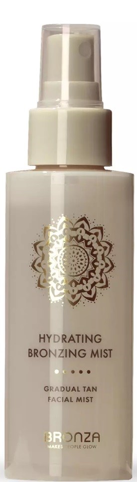 A white spray bottle labeled 'Hydrating Bronzing Mist' for gradual tan, with a decorative gold design on the front.