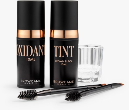 Two black bottles labeled Oxidant and Tint, glasses, and two small brushes with black handles and bristles.