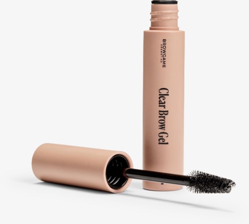 A beige brow gel tube with a black applicator lying beside it on a white background.