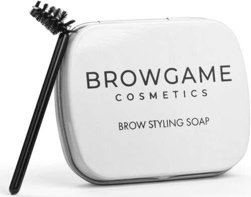 A white container of brow styling soap with a black brush leaning against it.