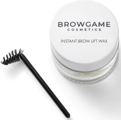 A jar labeled Browgame Cosmetics with eyebrow wax and a spoolie brush nearby.