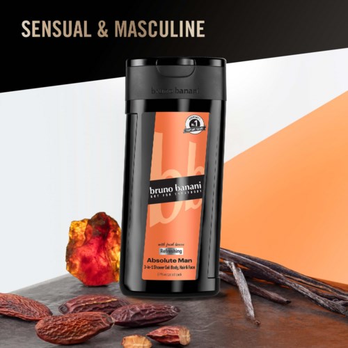 Een zwarte fles Bruno Banani Absolute Man deodorant met kruiden en geuren, samen met noten en kaneelstokken.