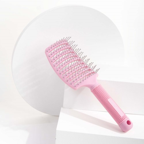 A pink hairbrush with metal bristles is resting on a white platform.