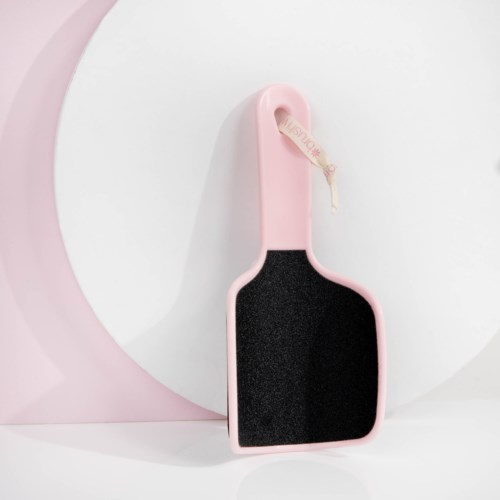 En liten, rosa rengöringsborste med svart scrubberområde hängande på en vägg.