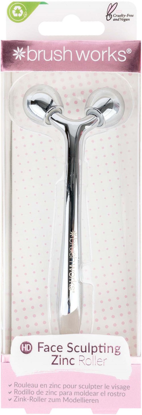 Een metalen zinkroller met twee bolvormige uiteinden, voor gezichtssculptuur, in verpakking met 'brushworks' en 'Face Sculpting Zinc Roller'.